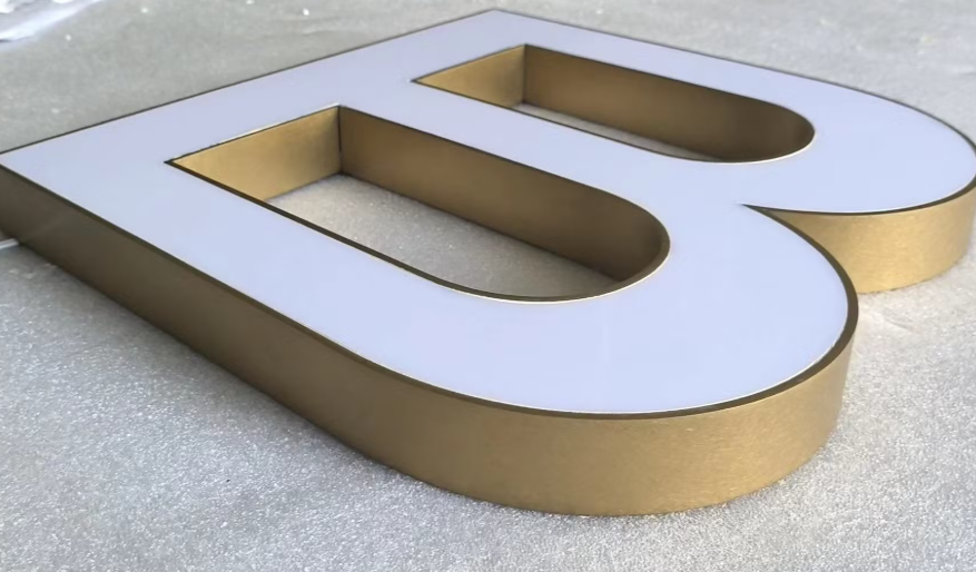 3D Channel Letter 'B' with white face and gold metallic sides showing professional fabrication